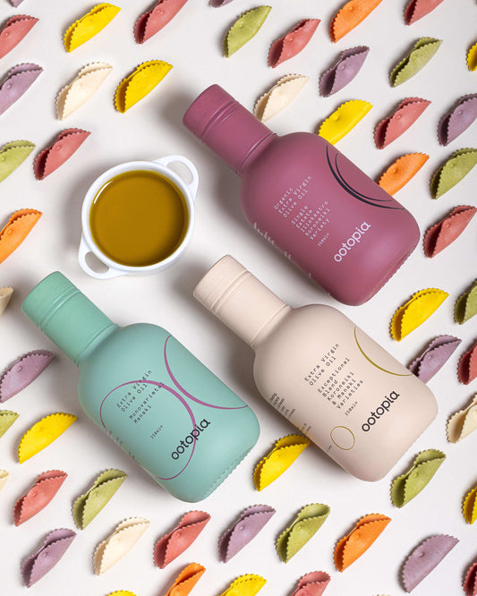 Ootopia's three-label set of olive oils surrounded by colorful pasta, highlighting their unique flavors and origins.