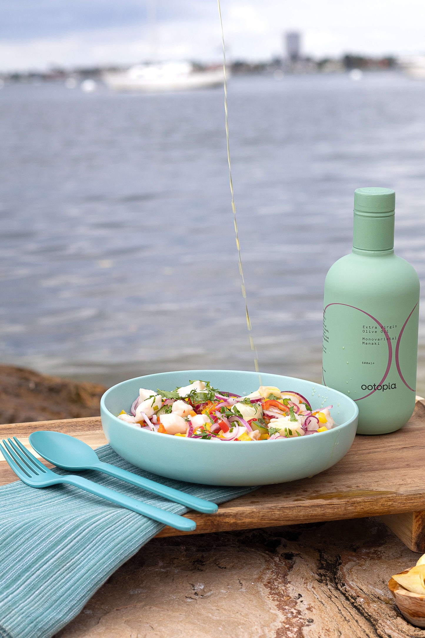 Plate of salad drizzled with Ootopia Greek Extra Virgin Olive Oil by the water.
