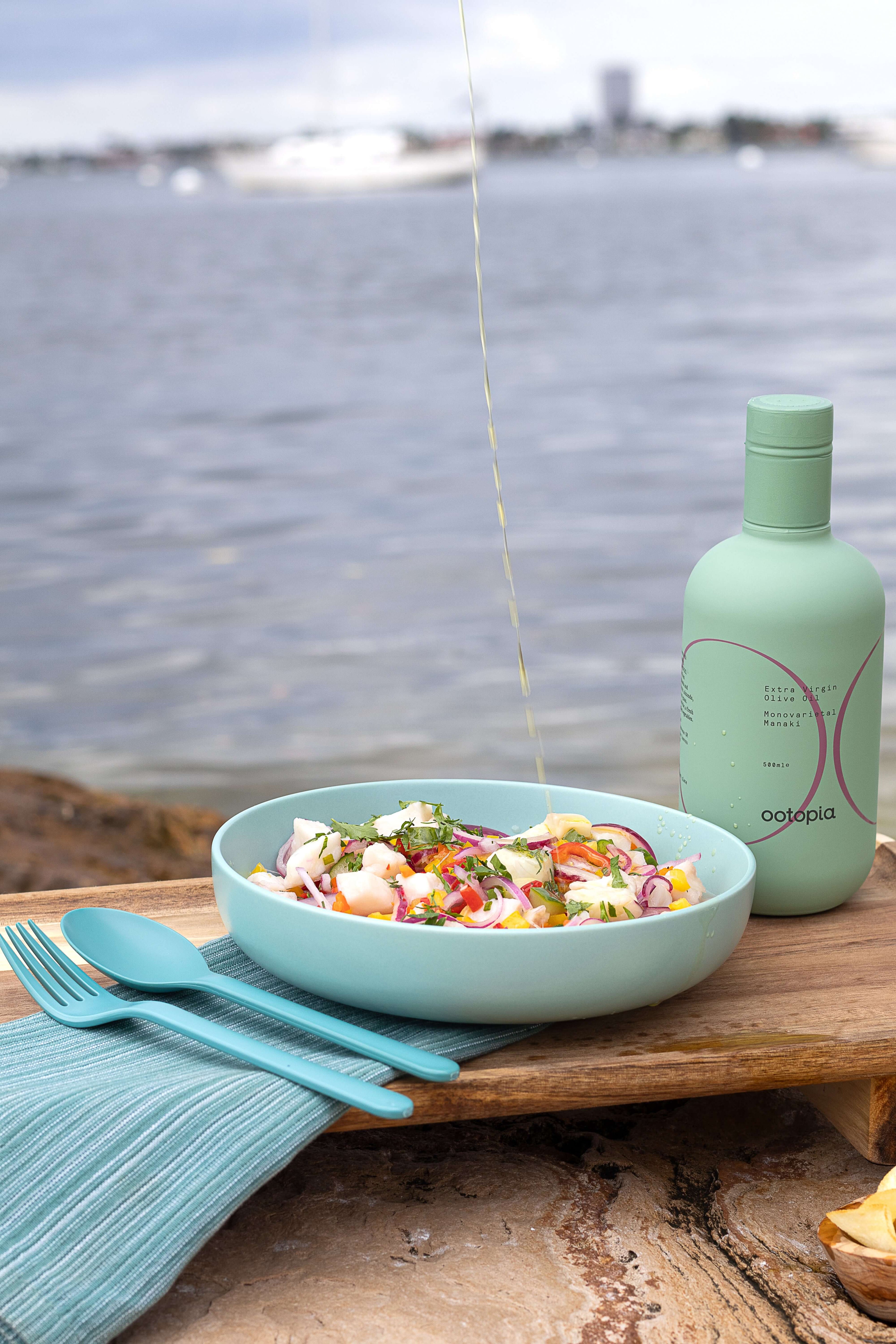 Plate of salad drizzled with Ootopia Greek Extra Virgin Olive Oil by the water.